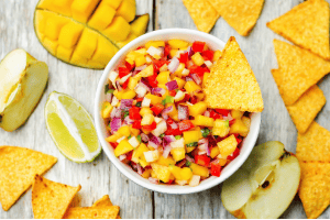 Dish of mango salsa with chunks of mango, tomatoes, peppers and red onion.