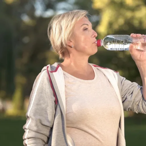 Woman drinking water. Hydration can help with menopause brain fog.