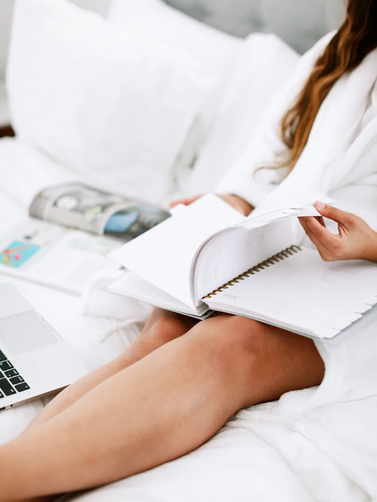 Woman reading book in robe on bed